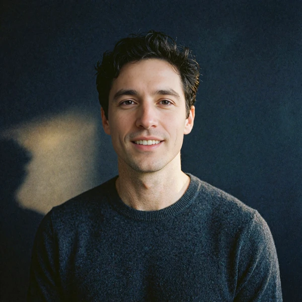 Portrait of a friendly young man in a charcoal knit sweater, representing an illustrative community voice