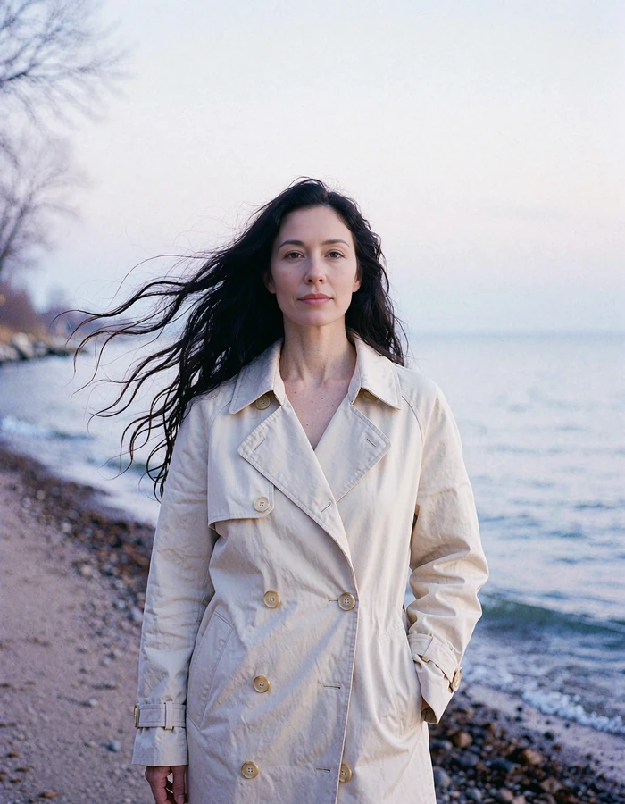 Elegant woman with long dark hair in a cream trench coat on a lakeshore path beside Lake Michigan - demonstration profile photo