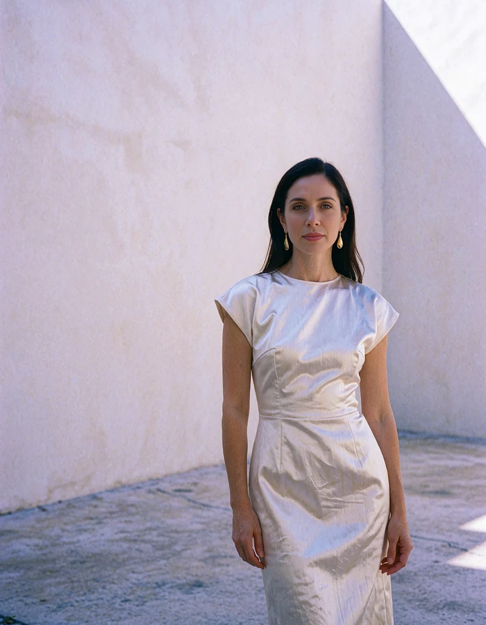 Woman with sleek dark hair and gold earrings in a minimal gallery courtyard in the Miami Design District - demonstration profile photo