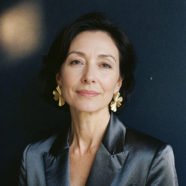 Portrait of a confident woman with sculptural gold statement earrings, representing an illustrative community voice